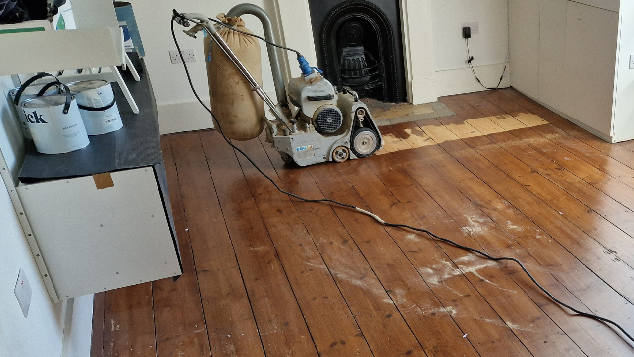 Dust-free sanding in progress on a solid pine floor during expert wood floor sanding in Catford home interior.