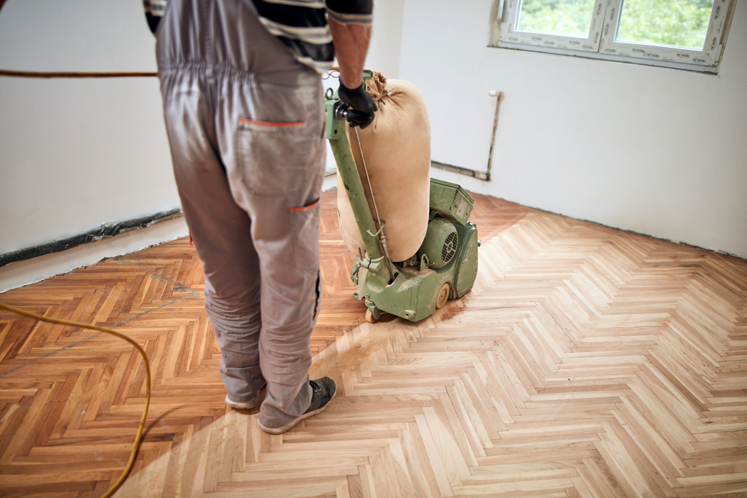 Technician using a drum sander on herringbone wood flooring during a Professional Wood Floor Sanding project in Catford.