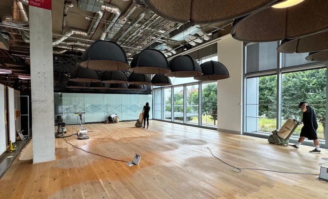 Pub Refurbs in Catford – live sanding of a wide-plank engineered oak floor with dust-extraction, technicians working in a light-filled bar space.