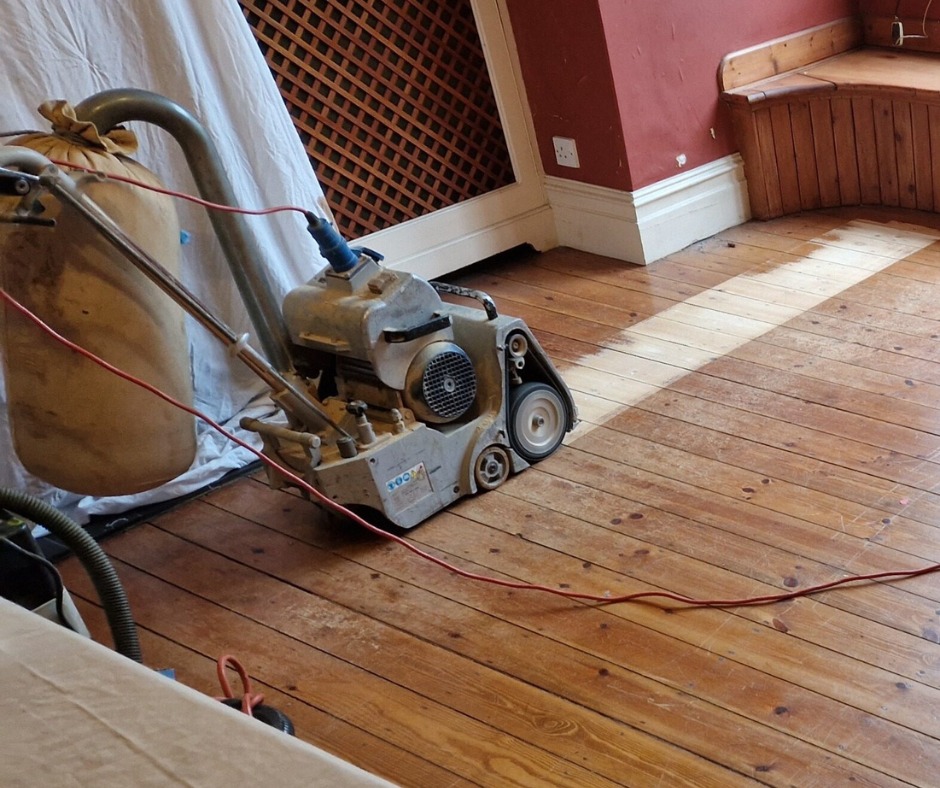 Wood Floor Sanding in Catford on pine softwood floorboards with a drum sander partway through the restoration.