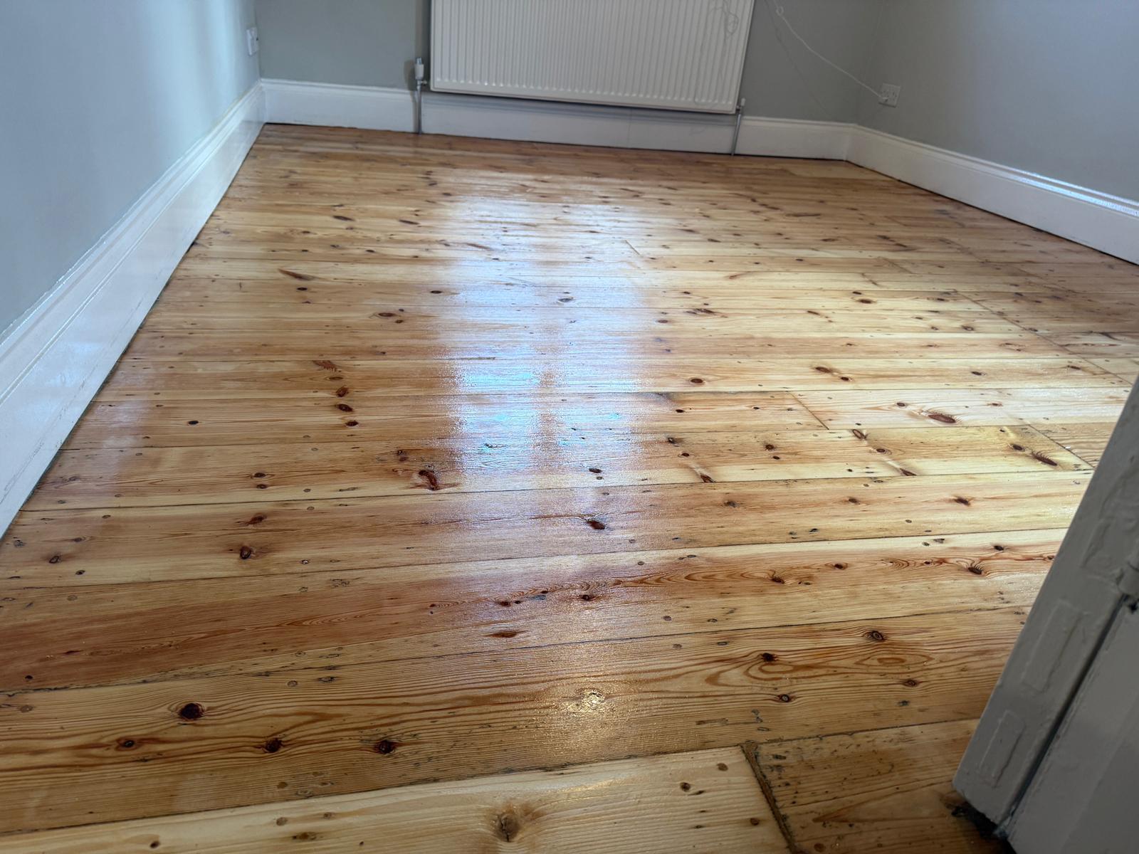Wood Floor Sanding in Catford on restored pine softwood floorboards in a freshly decorated bedroom.