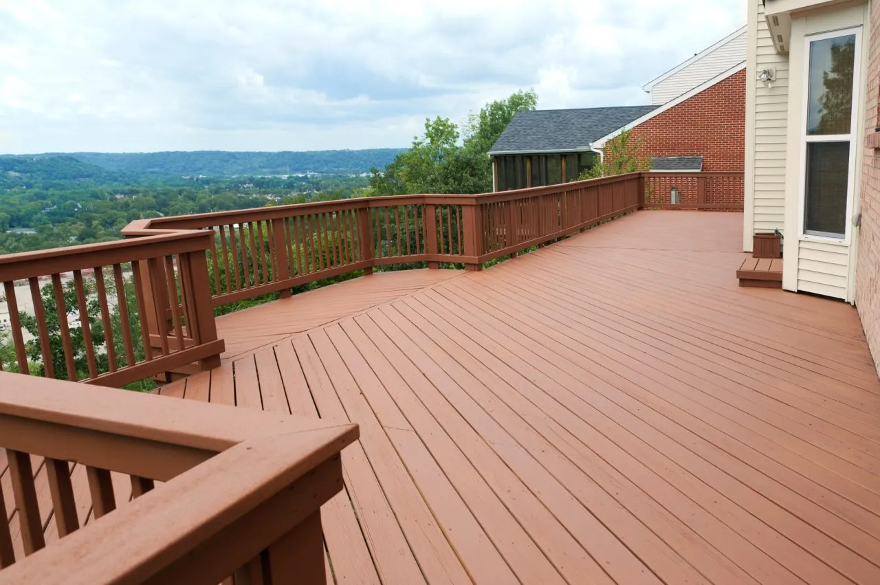 Large softwood terrace decking floor after Deck Sanding and Renewal in Catford, showing a smooth, freshly finished raised deck with railings overlooking green countryside.
