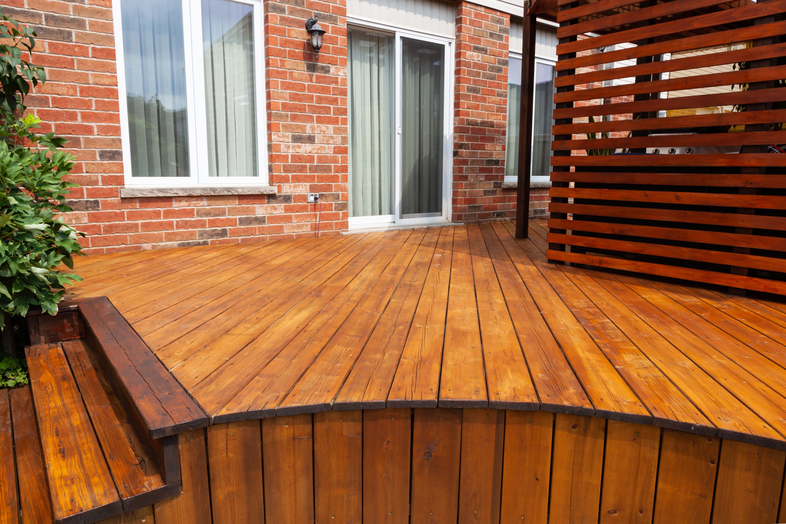 Freshly finished raised softwood timber garden decking floor after Deck Sanding and Renewal in Catford, creating a warm outdoor terrace beside a red-brick house.