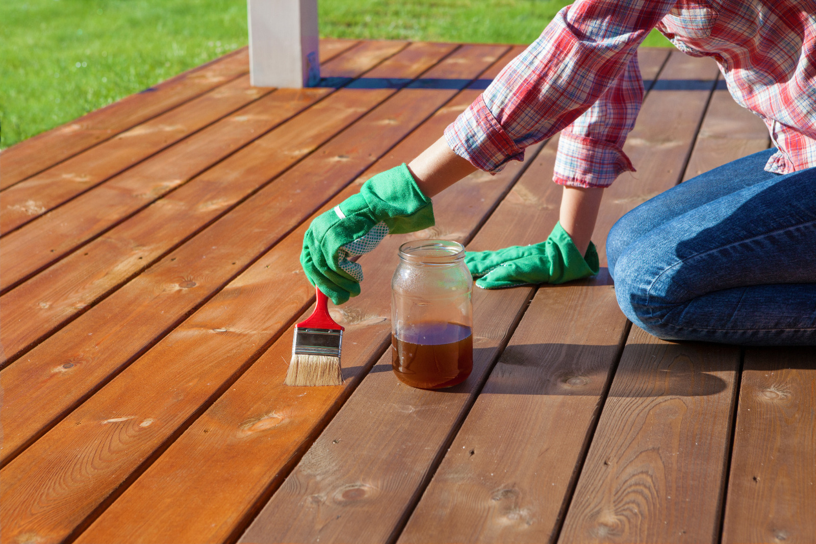 Homeowner applying oil after Deck Sanding and Renewal in Catford on softwood garden deck floorboards, showing the rich new colour against the previously weathered timber.