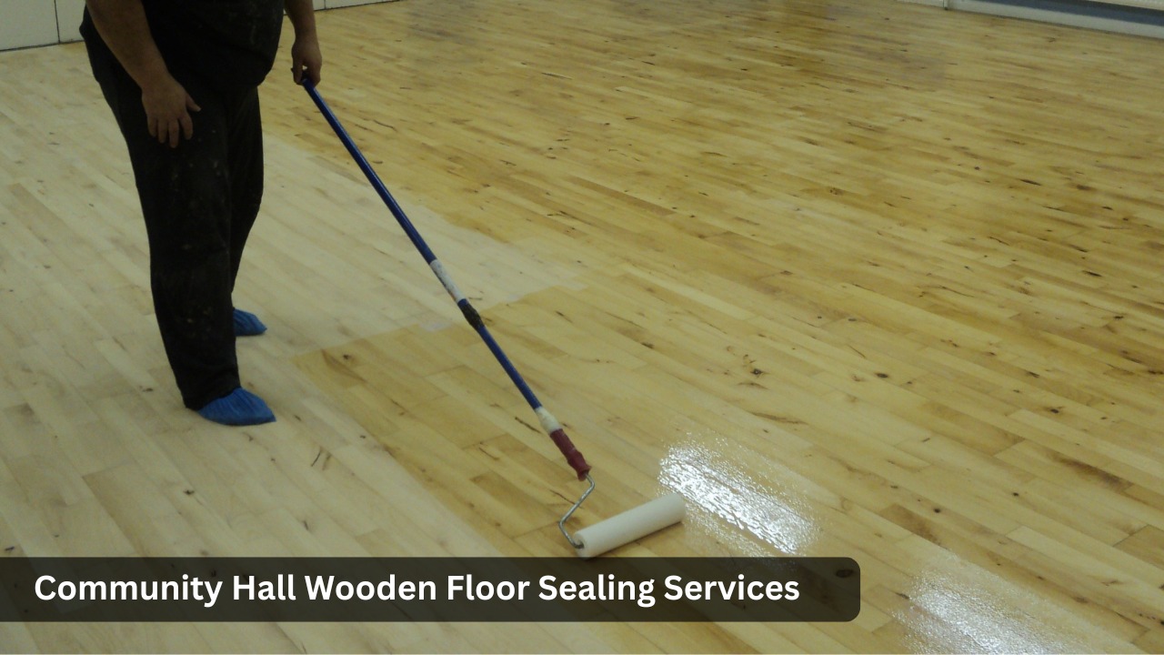 Professional applying clear sealant with a roller to a wooden community hall floor during dust-free floor sealing service